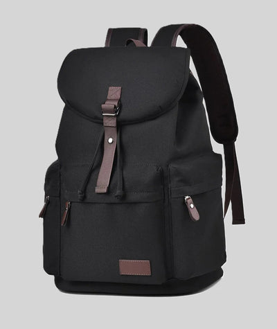 Black backpack with brown leather buckle strap, top flap, front pockets, and padded shoulder straps.