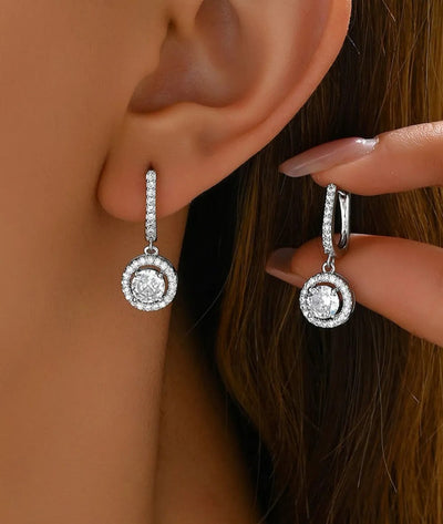 Silver-tone diamond halo drop earrings with pavé hoop and round center stone in circular halo.
