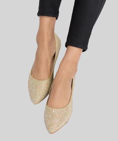 Gold glitter slip-on loafers with pointed toes worn with black pants.