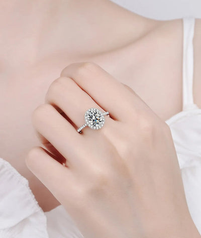 Halo engagement ring with a round center diamond and pave band on a slim silver setting.