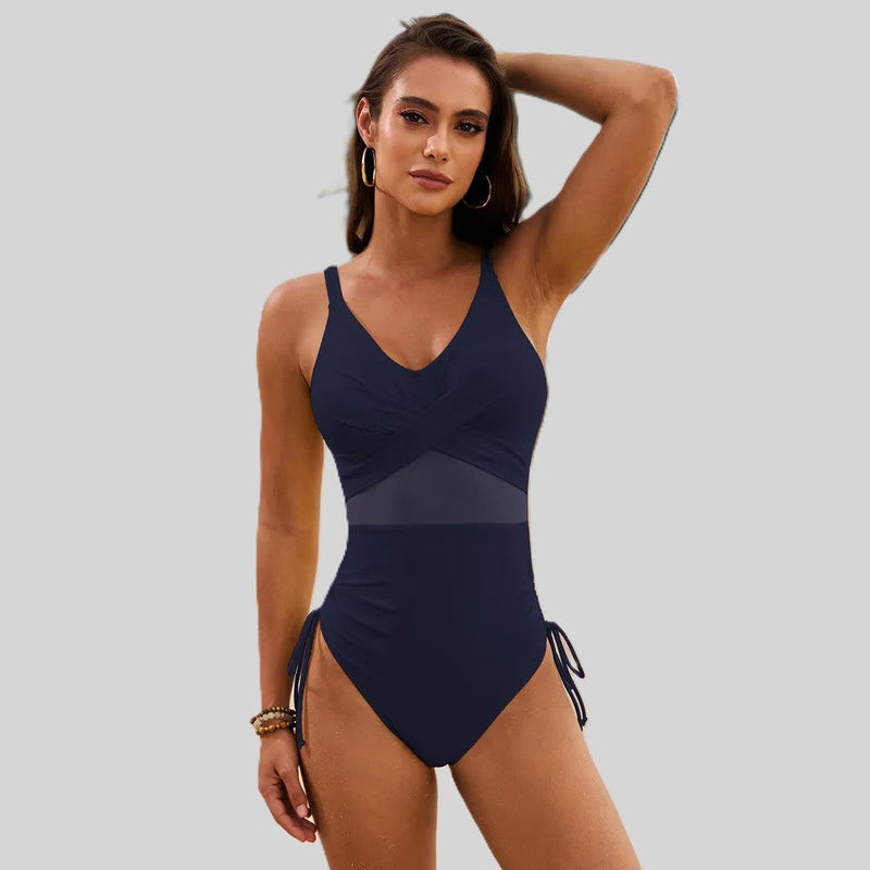 Woman in navy blue swimwear with sheer mesh waist panel and side ties.