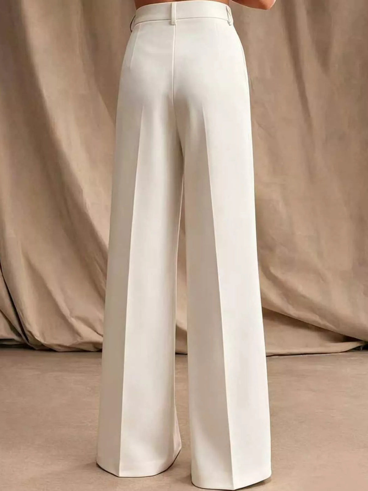 Off-white high-waisted pleated wide-leg pants, back view with belt loops