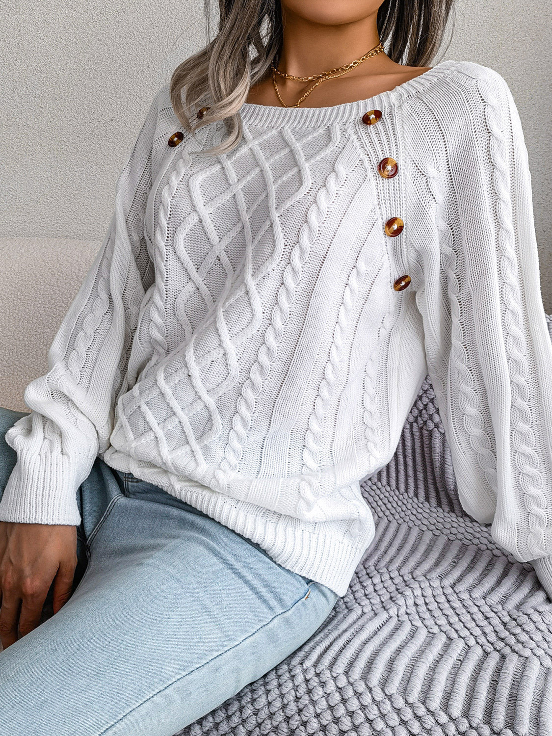 White cable-knit sweater with diamond lattice front and decorative shoulder buttons