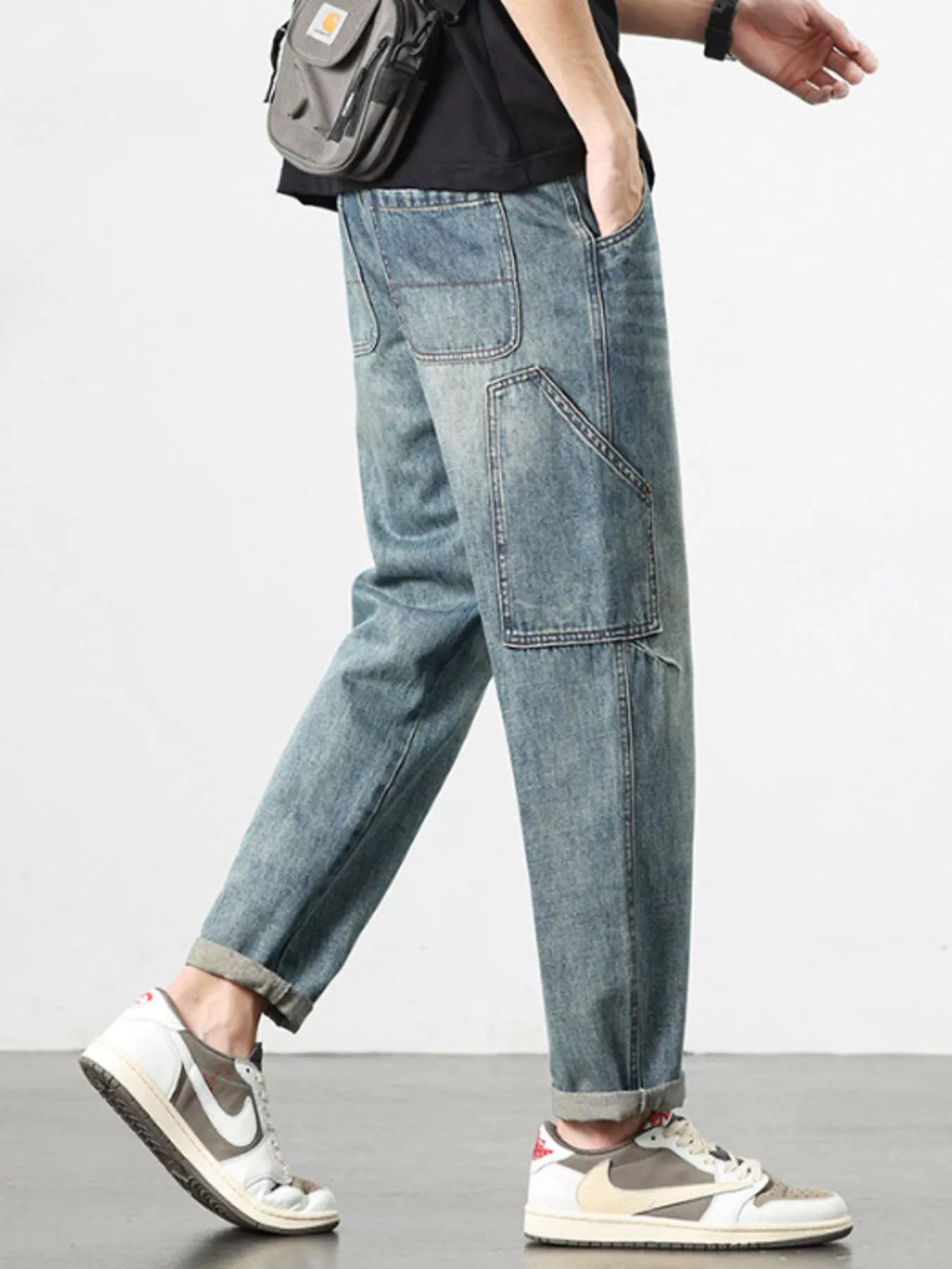 Relaxed washed blue jeans with thigh patch pockets and stitched seams.