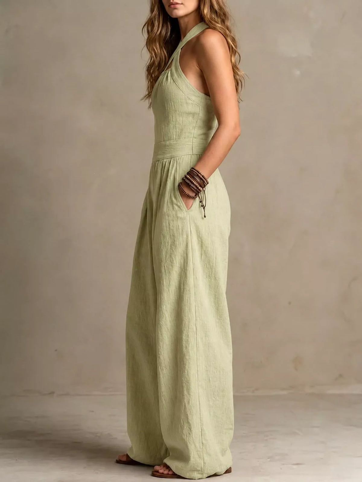 Sage green halter linen jumpsuit with high waist seam and wide, draped pant legs