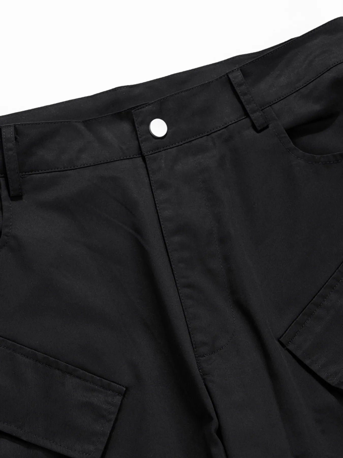 Black cargo pants waistband with belt loops and button closure, close-up.