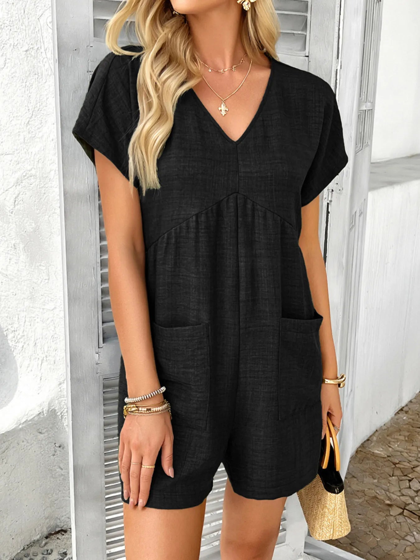 Black V-neck short-sleeve romper with front pockets and relaxed shorts legs