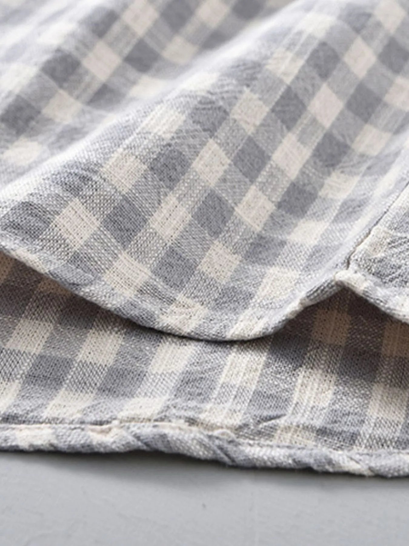 Gray plaid button-up shirt cuff and hem close-up with stitched edge
