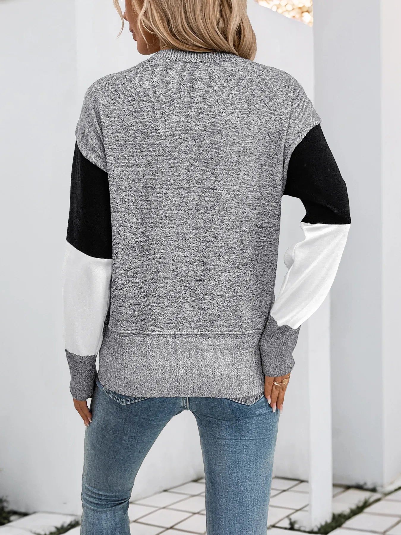 Back view of grey, black, and white color-block knit long-sleeve sweater