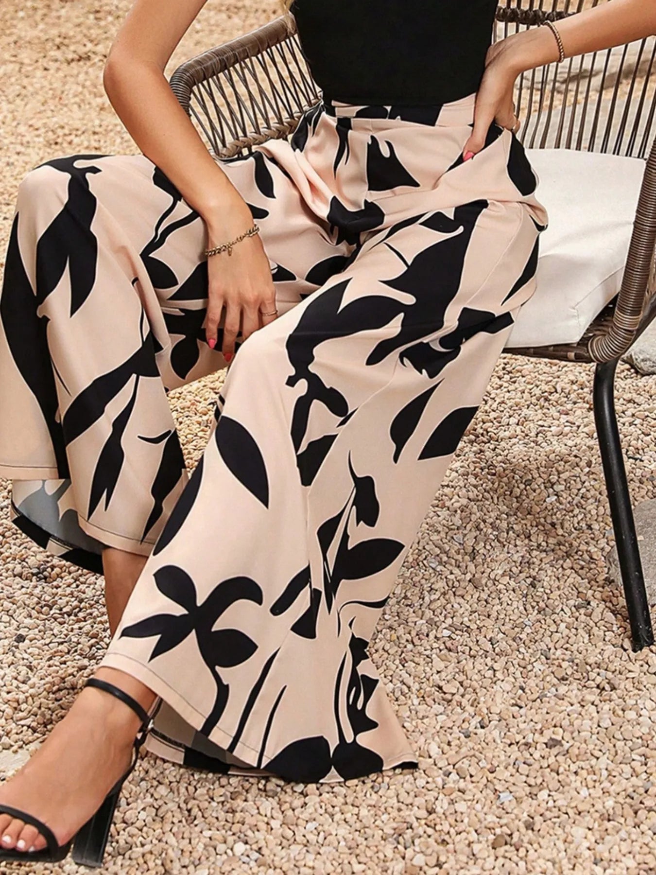 Printed wide-leg pants with tan base and bold black foliage print, drapey fit.
