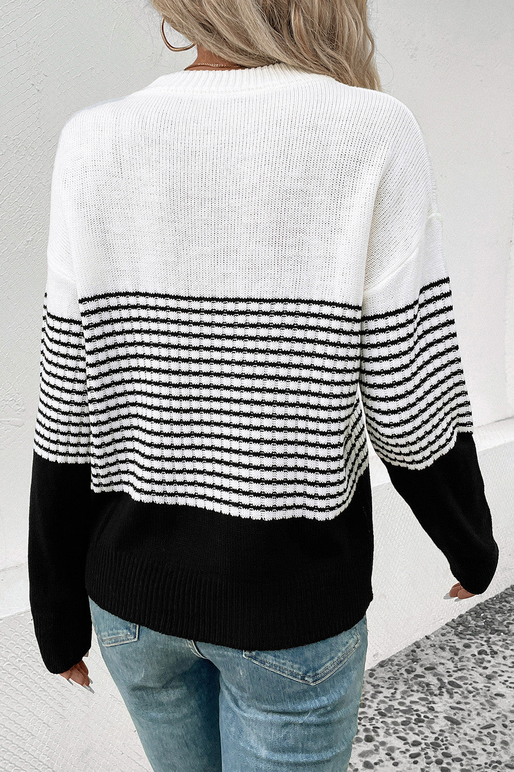 Back view of striped drop-shoulder sweater, white with black horizontal bands and ribbed cuffs
