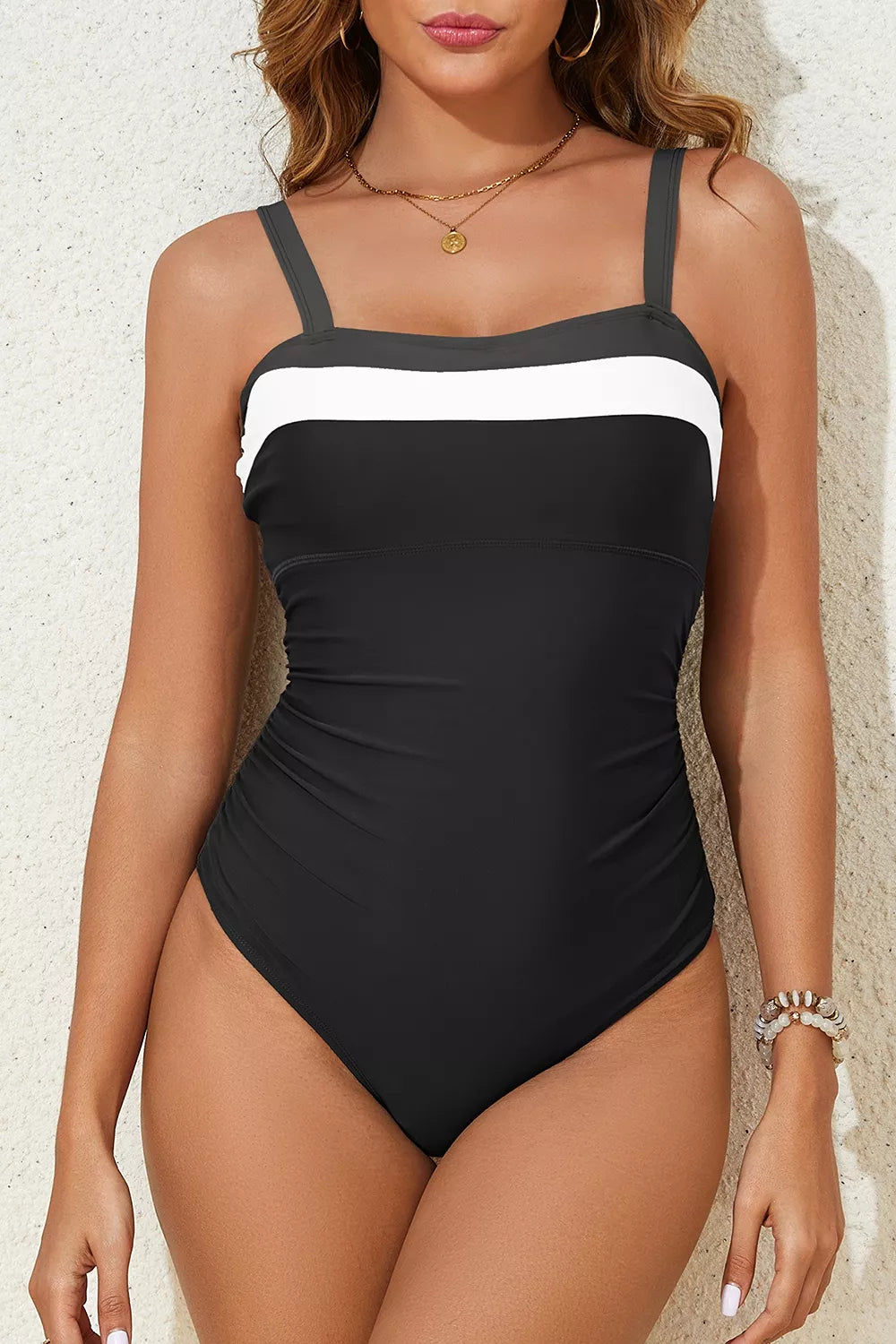 Black one-piece swimsuit with white stripe band and adjustable shoulder straps, ruched