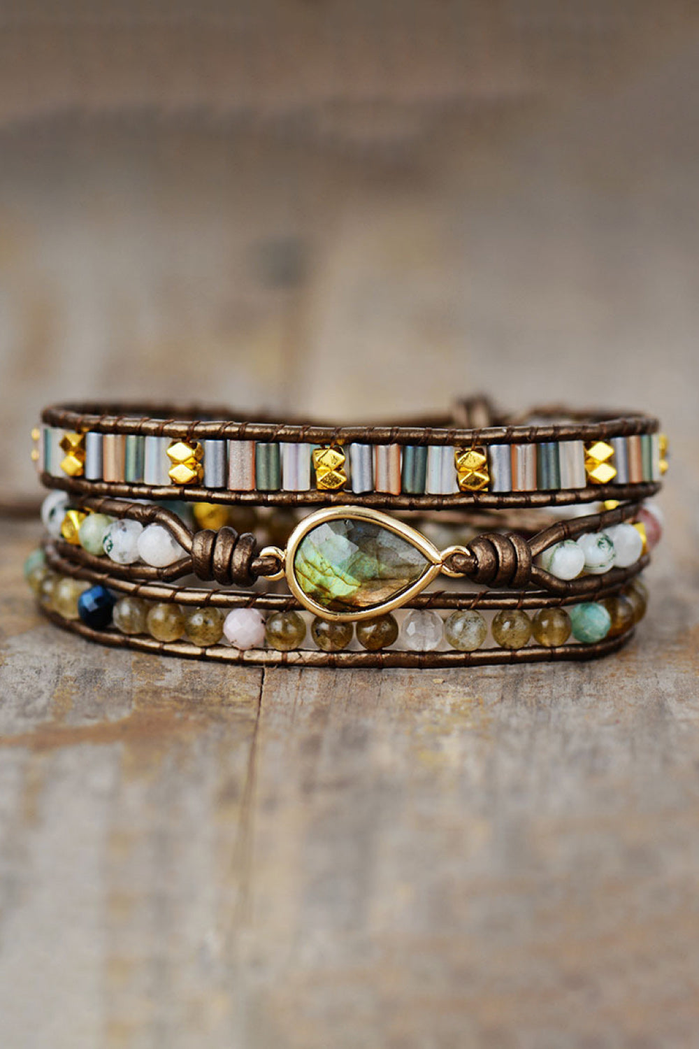 Triple-layer beaded bracelet with brown wrap, oval green center charm, glass beads