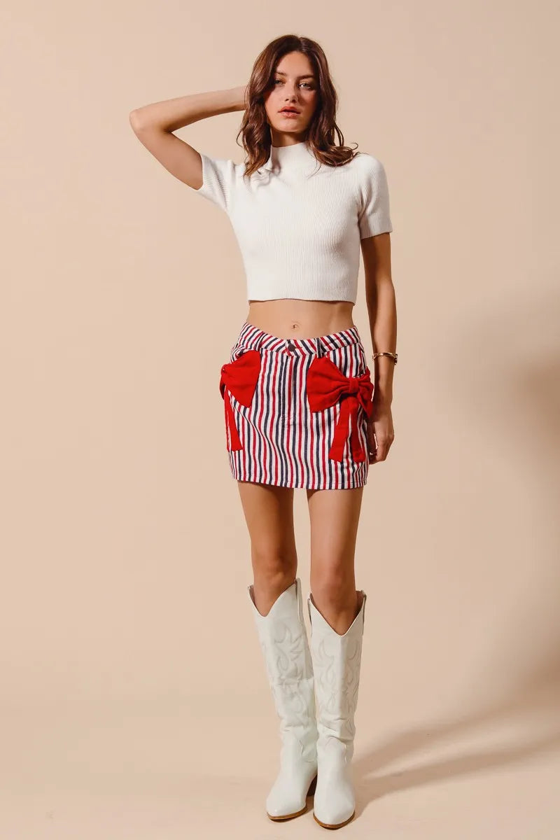 Striped denim mini skirt with red bow tie front and tassel pocket accents