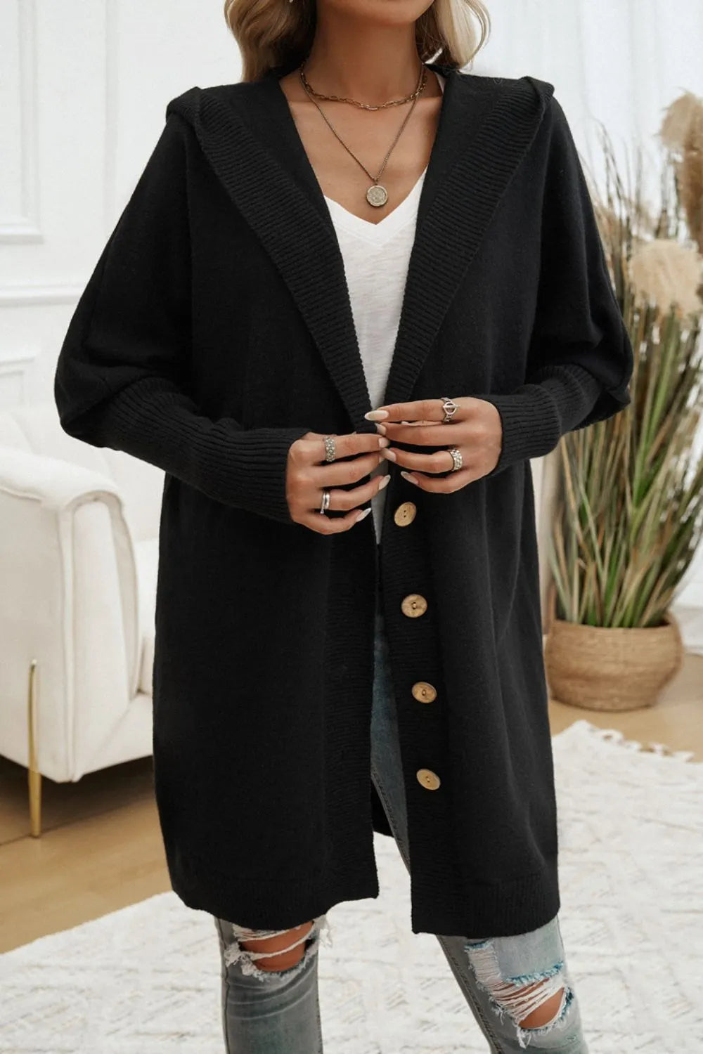 Black hooded button-up cardigan with long sleeves and gold button accents.
