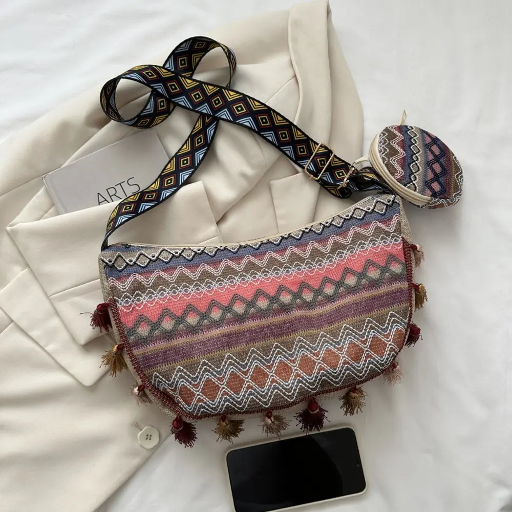 Printed crossbody bag with colorful zigzag stripes, tassel edges, and coin pouch.