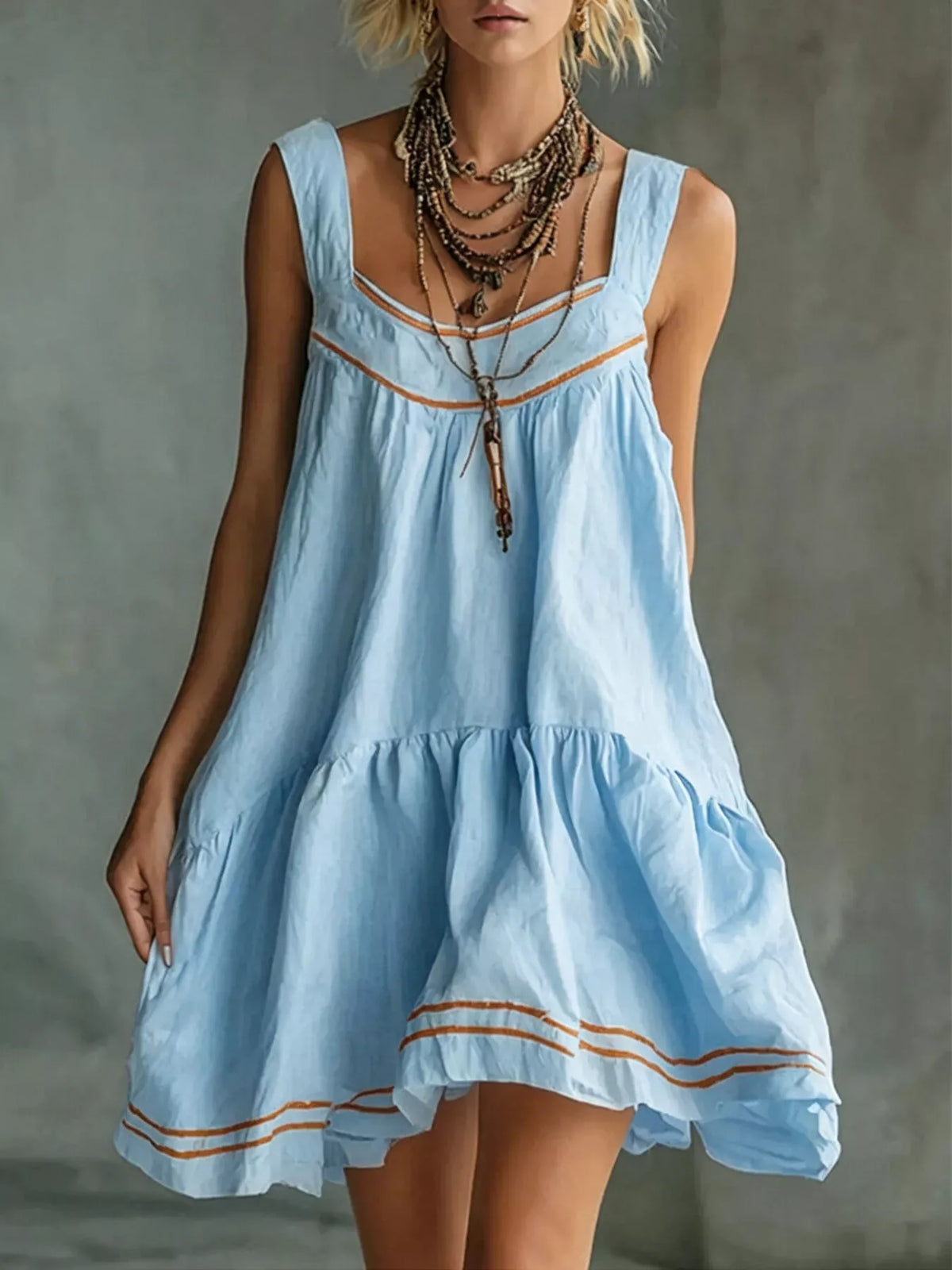 Light blue sleeveless tiered ruffle mini dress with orange trim and layered hem