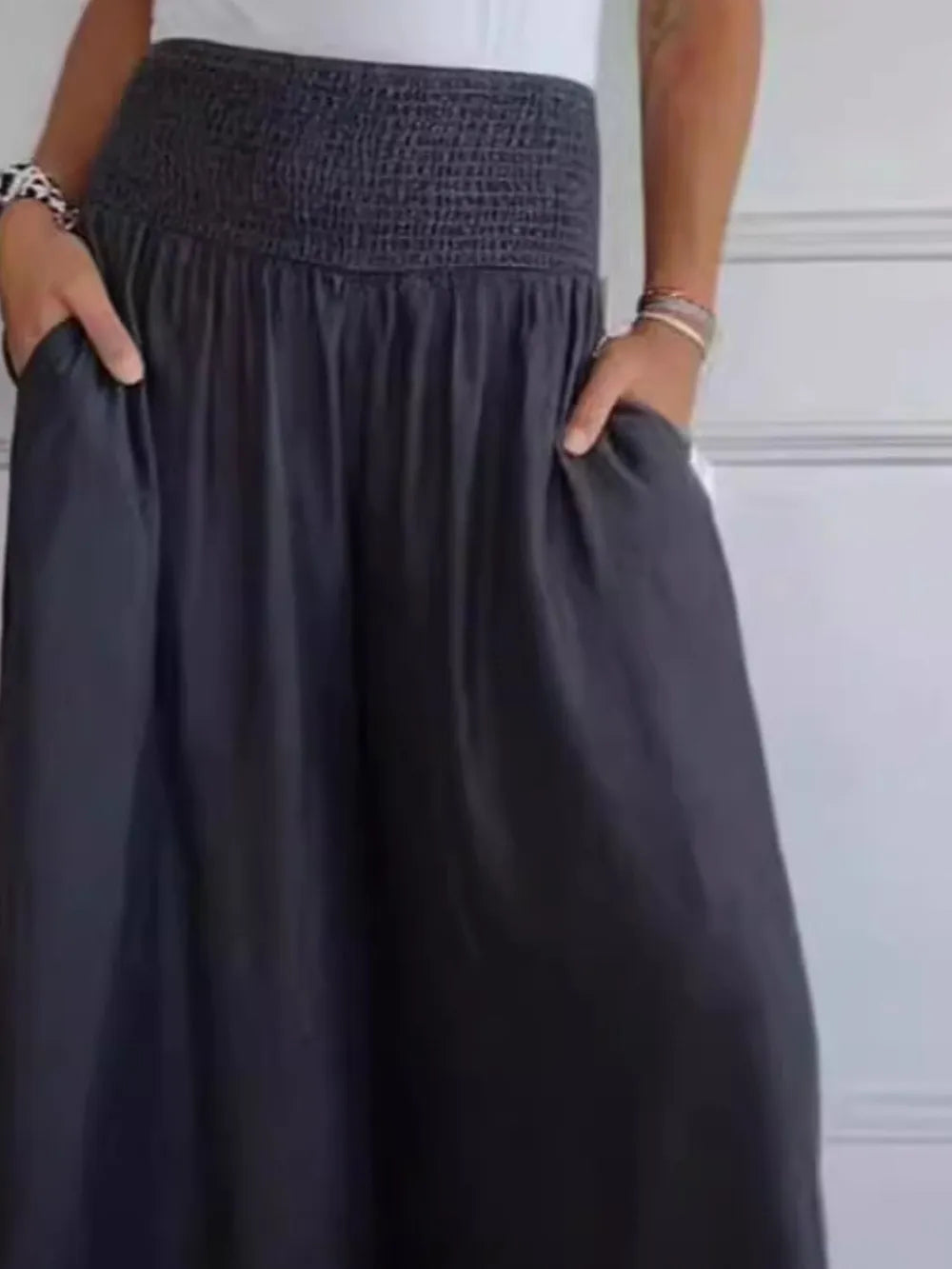 Dark smocked waist wide-leg pants with relaxed, gathered skirt silhouette