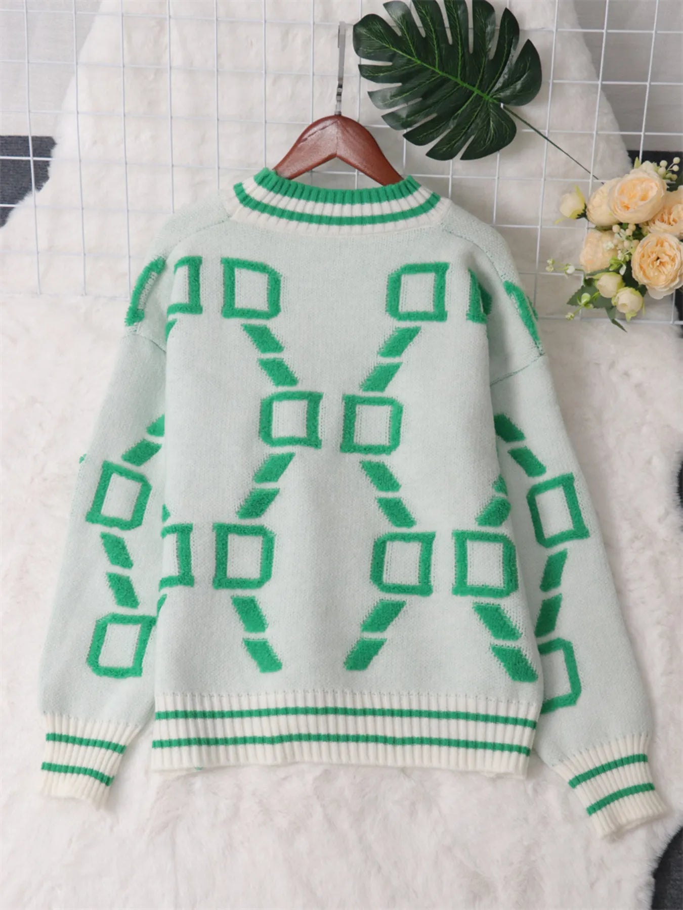 White round-neck long-sleeve sweater on hanger with green geometric back pattern