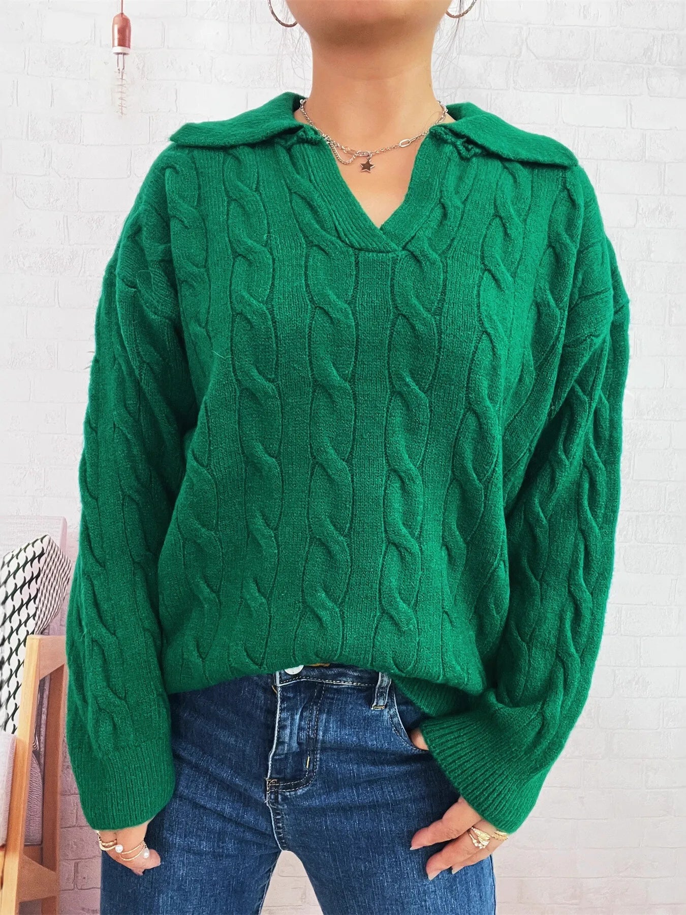 Green cable-knit johnny-collar sweater with long sleeves and chunky cable pattern.