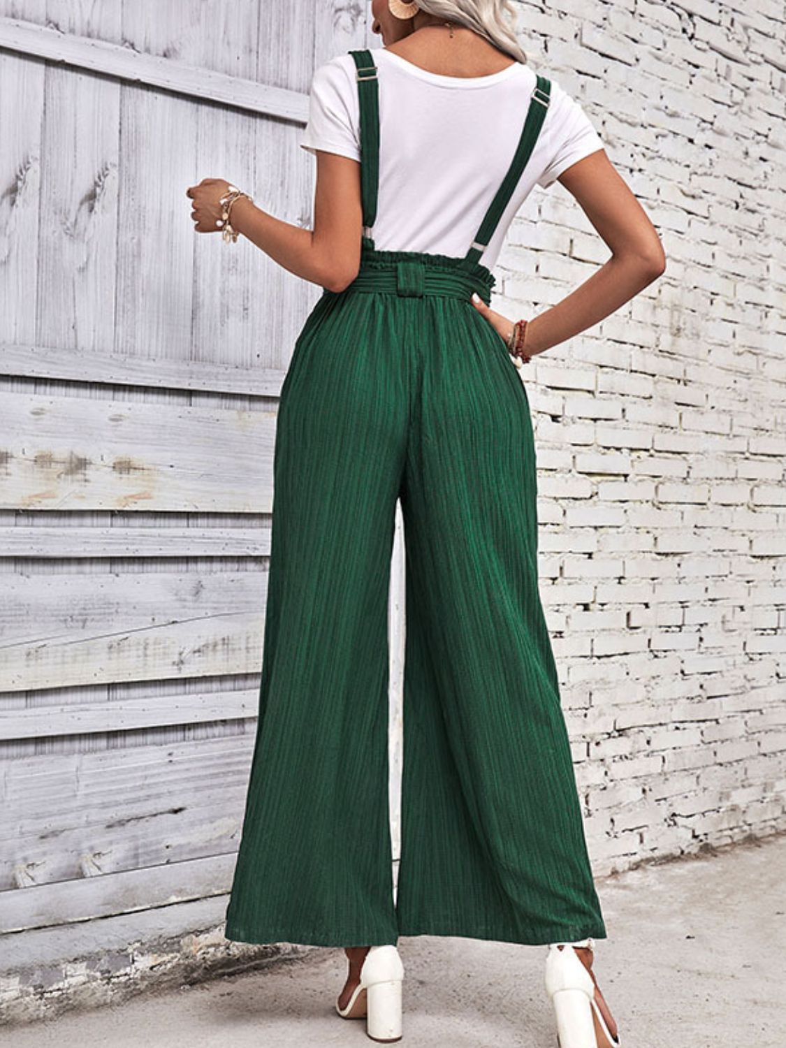 Dark green wide-leg overalls with bib front, suspender straps, and tied waist