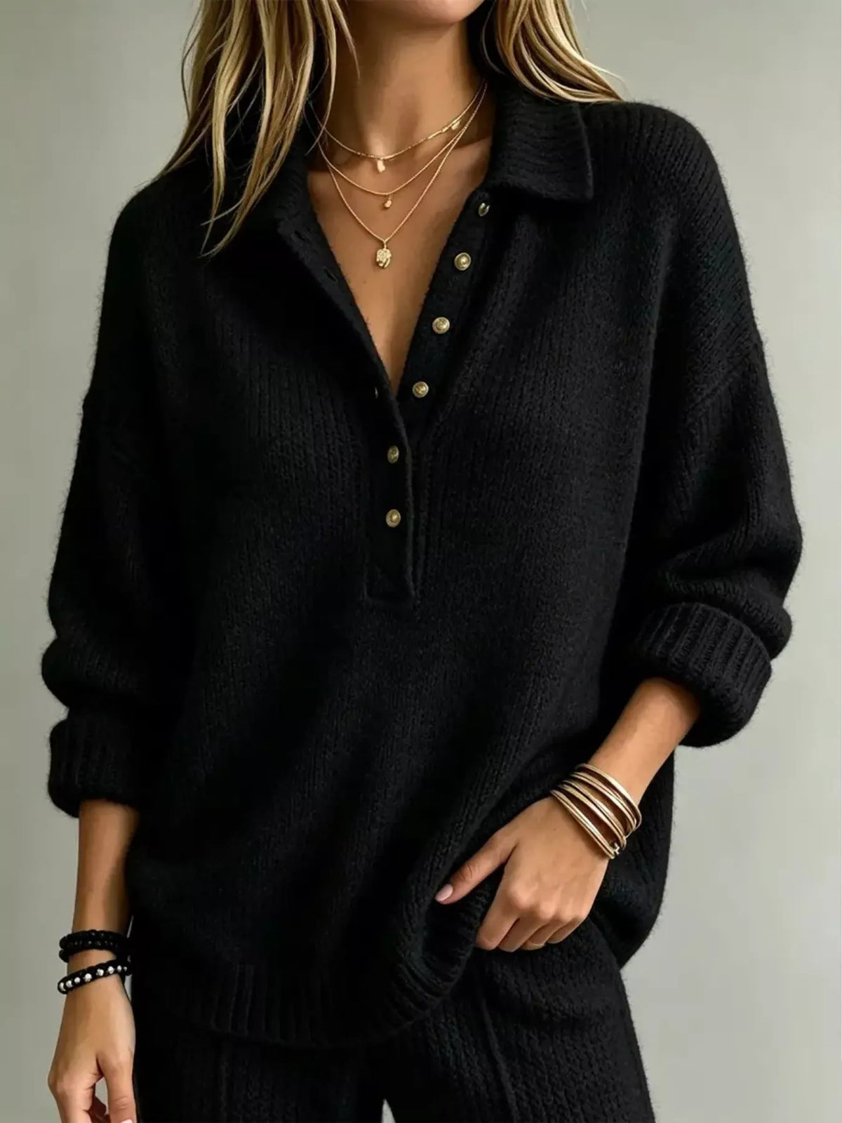 Black button-front dropped-shoulder sweater with henley placket and gold-tone buttons.