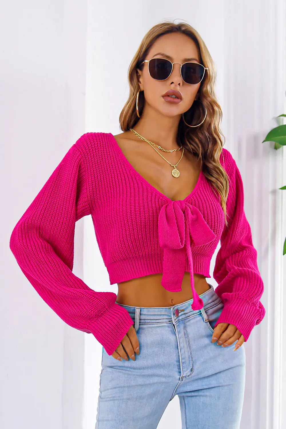 Deep rose knit cropped sweater with long sleeves, V-neck and front bow.