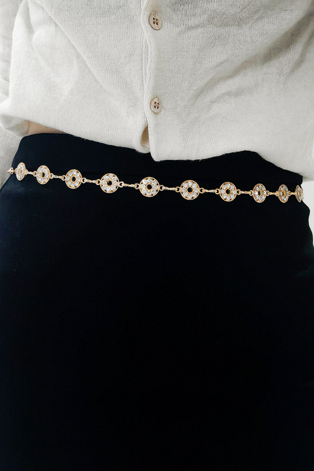 Gold rhinestone chain belt with round crystal links, worn over dark skirt