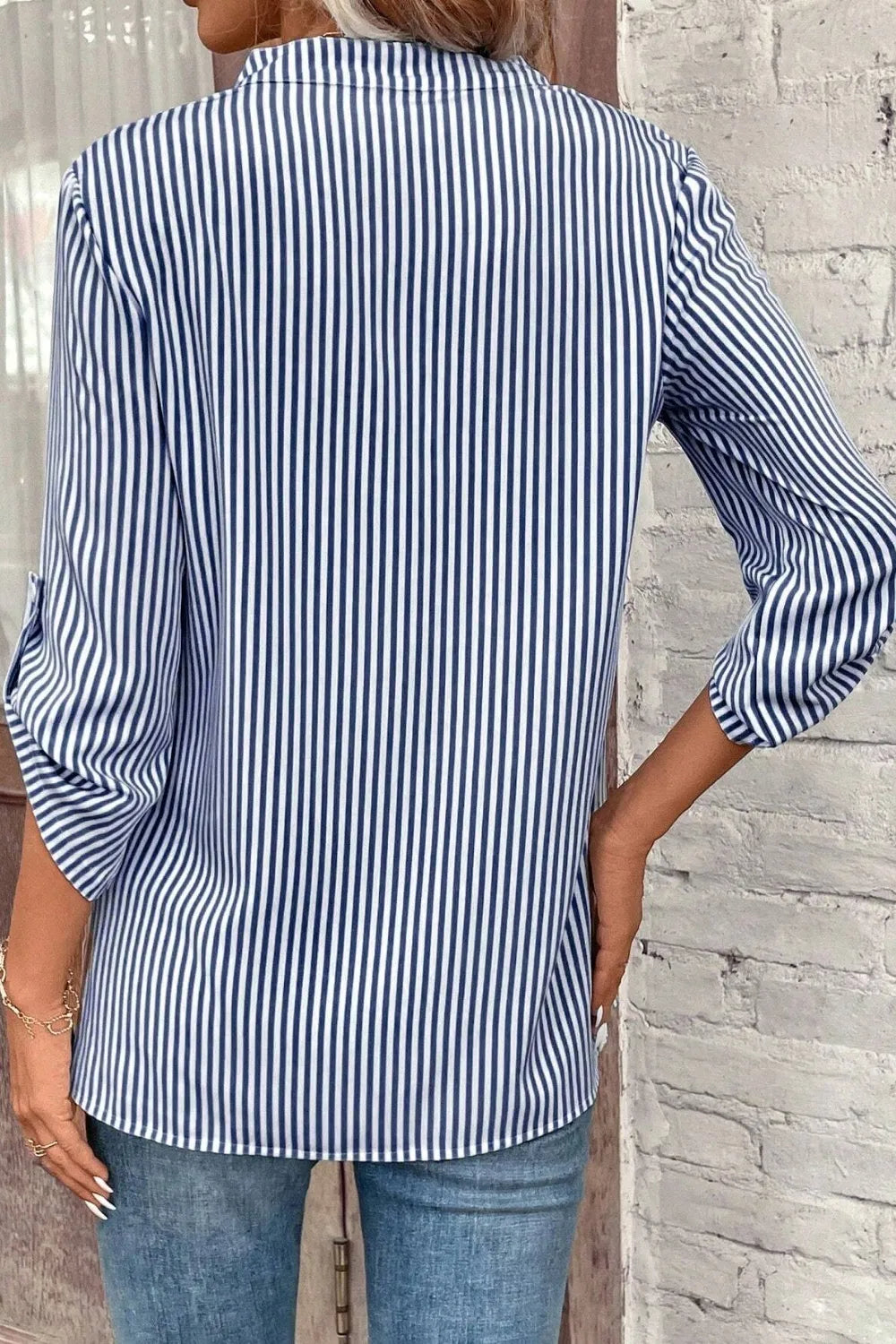 Light blue striped roll-tab sleeve shirt from the back with vertical stripes
