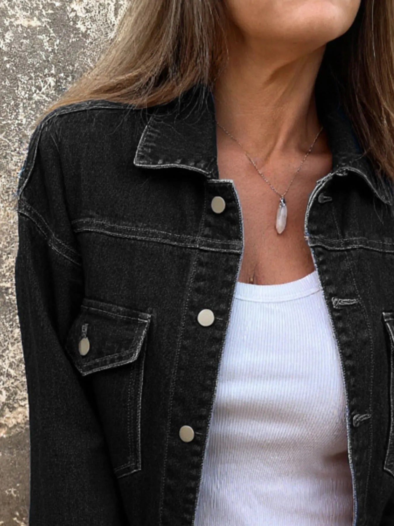 Black denim jacket with button front and flap chest pockets, long sleeves