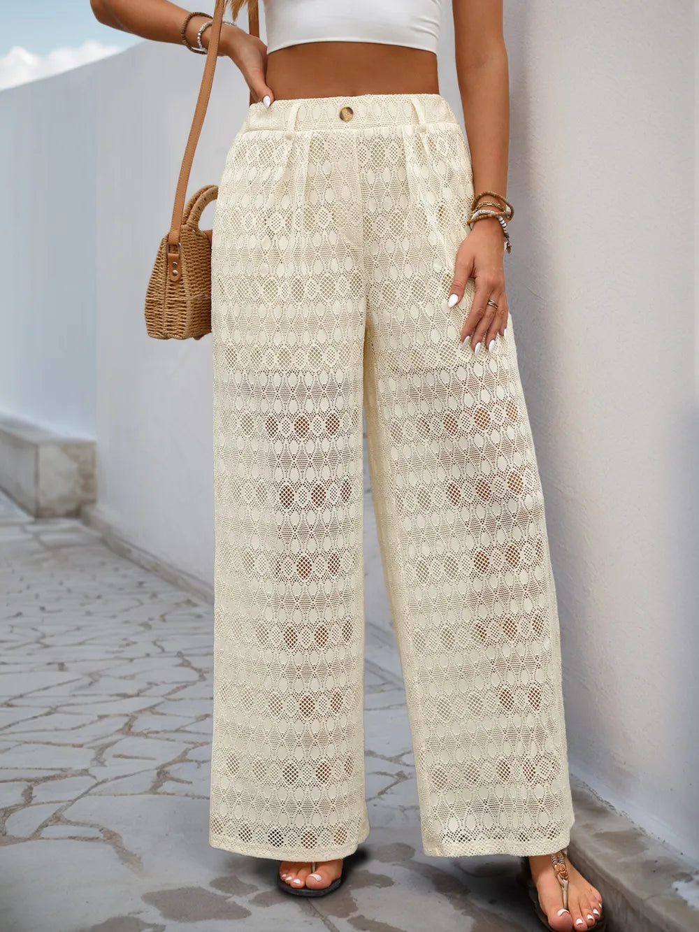Cream wide-leg lace pants featuring decorative button waistband and openwork geometric pattern