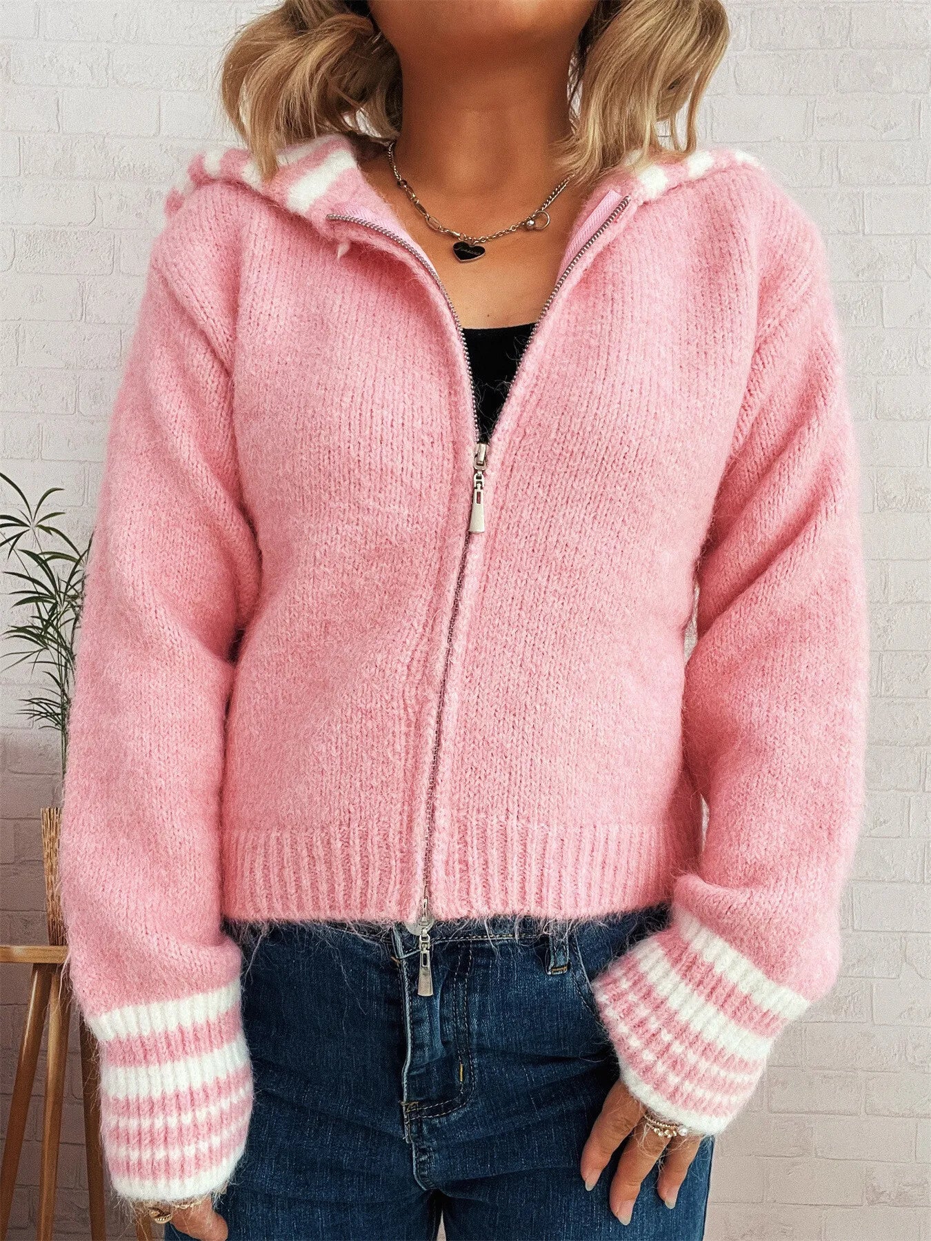 Pink zip-up cardigan with striped ribbed cuffs and visible zipper pull