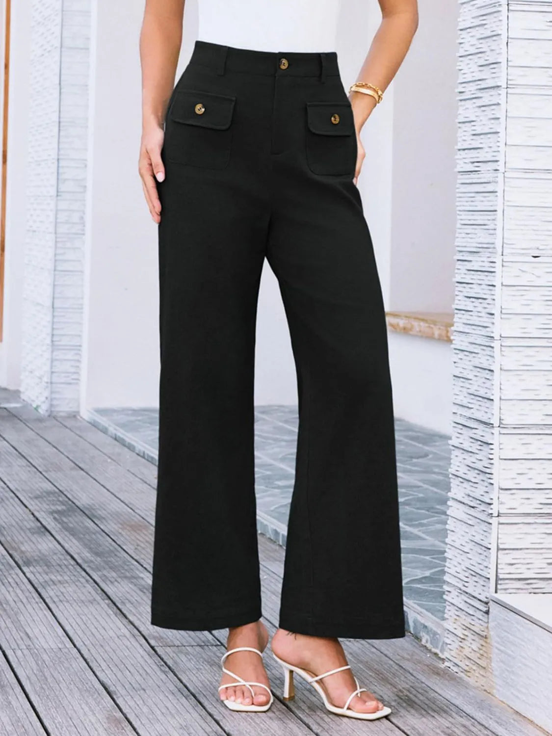 High-waist wide-leg pants, black; high waist with side flap pockets and gold buttons.