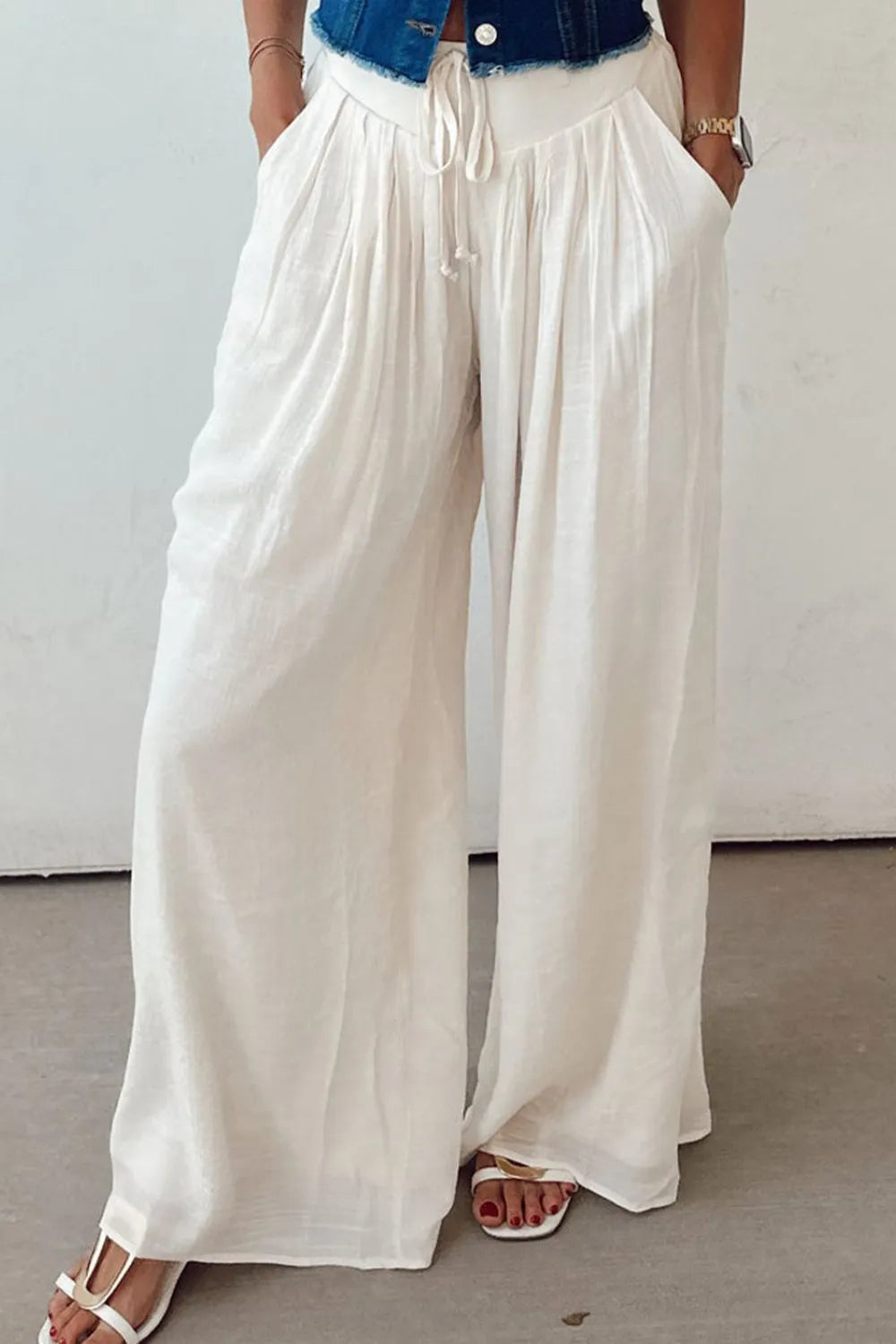 White pleated wide-leg pants with tie waist, loose fit, and flowy drape