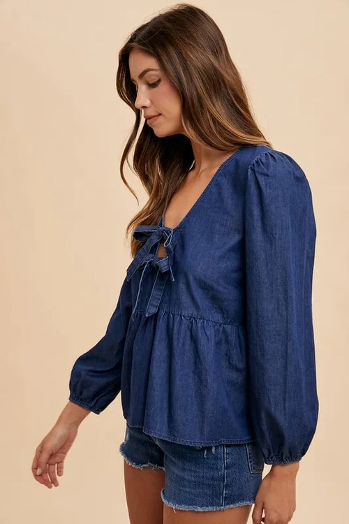 Navy denim tie-front peplum long-sleeve top, side view with bow detail