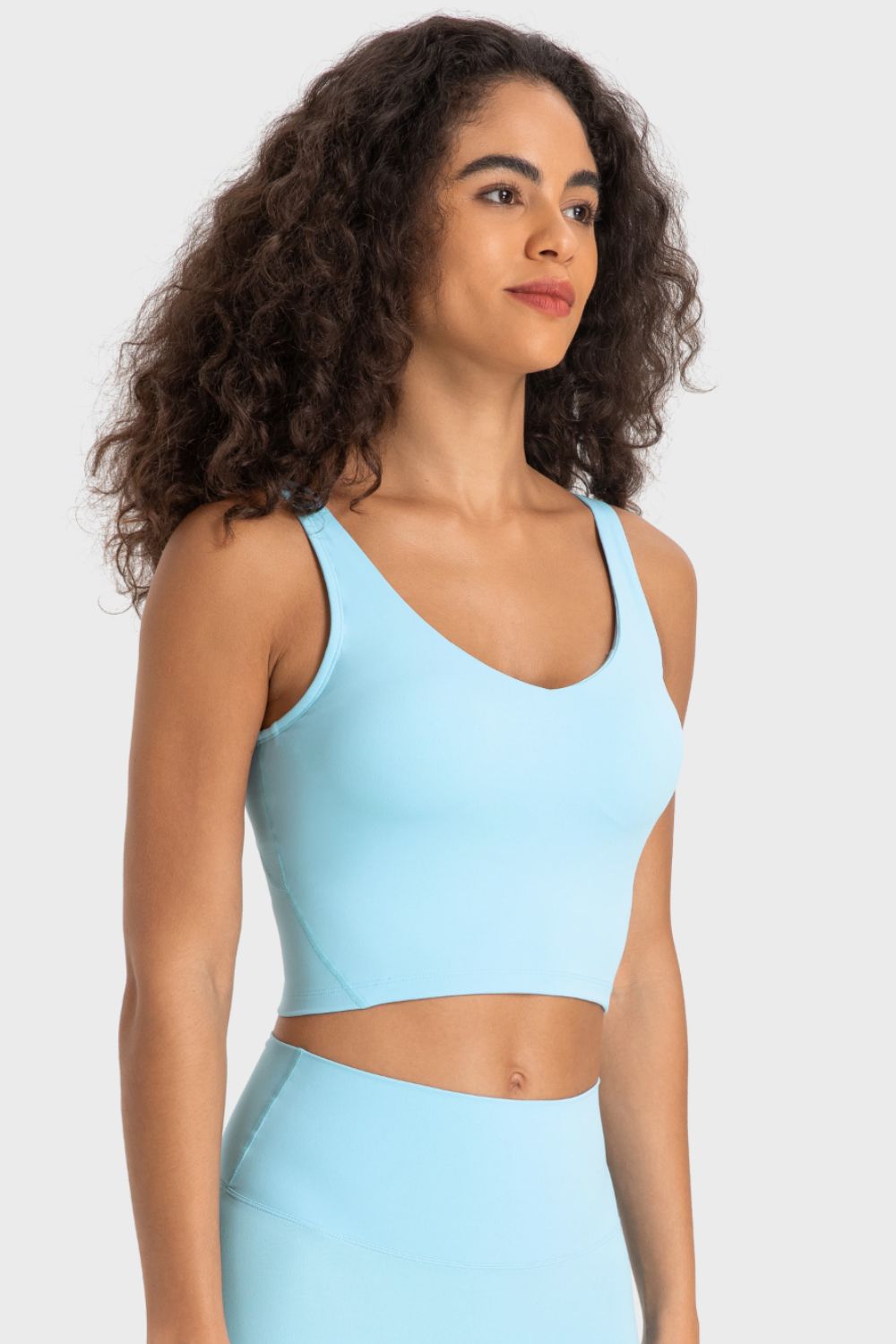 Deep V-neck crop sports bra, light blue color, side profile.