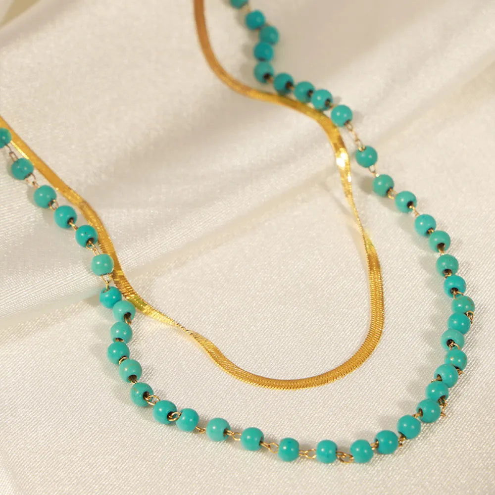Double-layer necklace with gold chain and turquoise beads, close-up on links