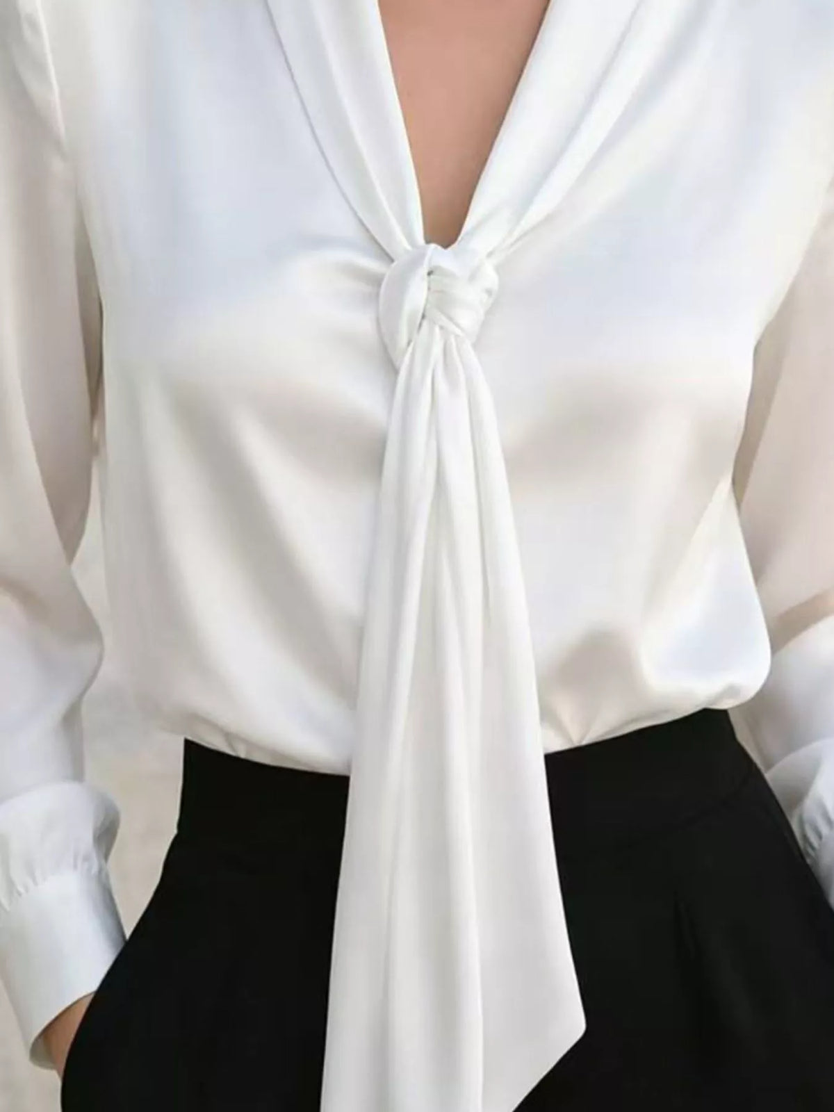 White satin blouse close-up of V-neck tie knot and draped fabric