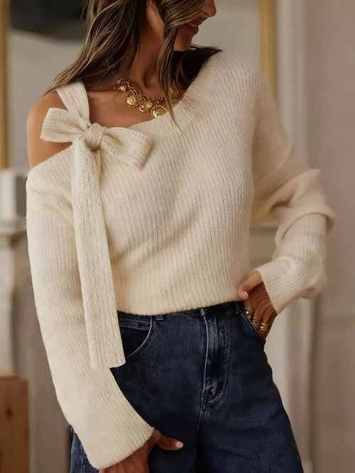 Beige one-shoulder knit sweater with bow tie accent at left shoulder