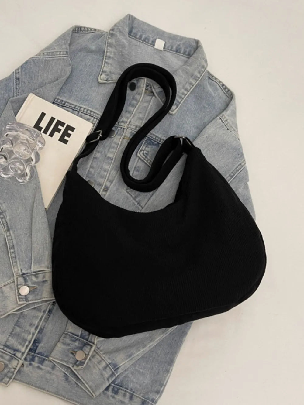 Black ribbed shoulder bag with adjustable strap and drawstring top