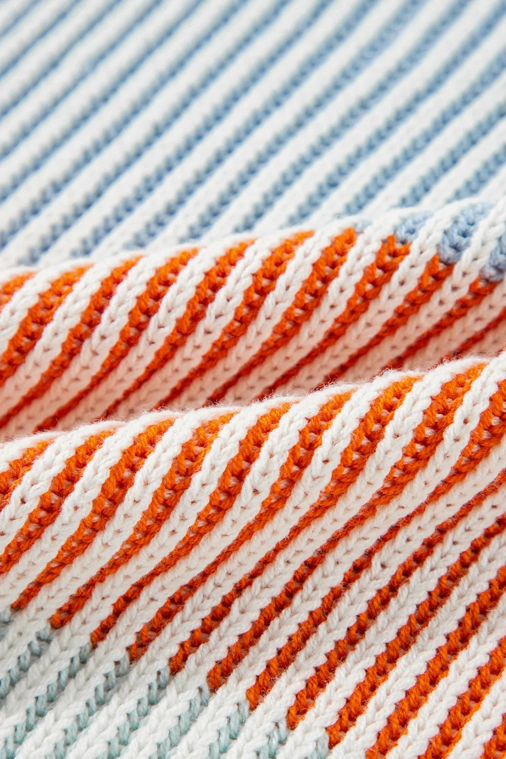 Knit fabric close-up of color-block striped sweater in cream, dusty pink, mint, and orange