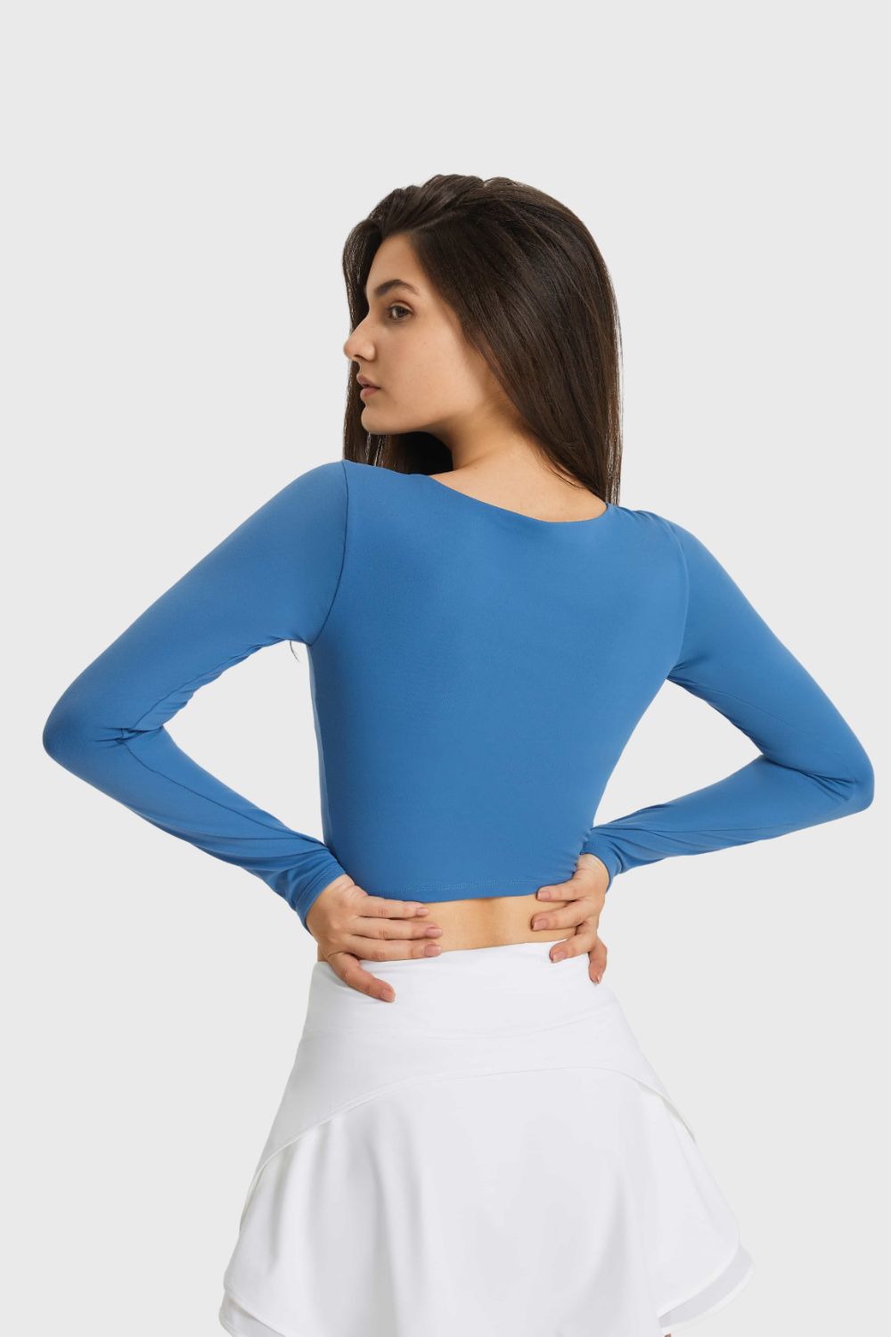Blue long-sleeve cropped sports top, side view with waist cutout