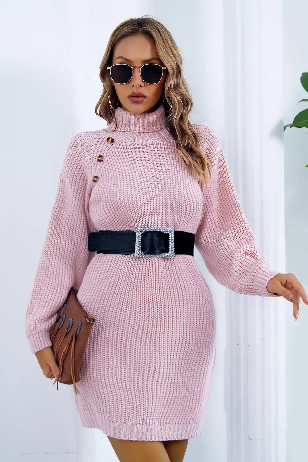 Pink knit turtleneck sweater dress with long sleeves, side buttons and black belt