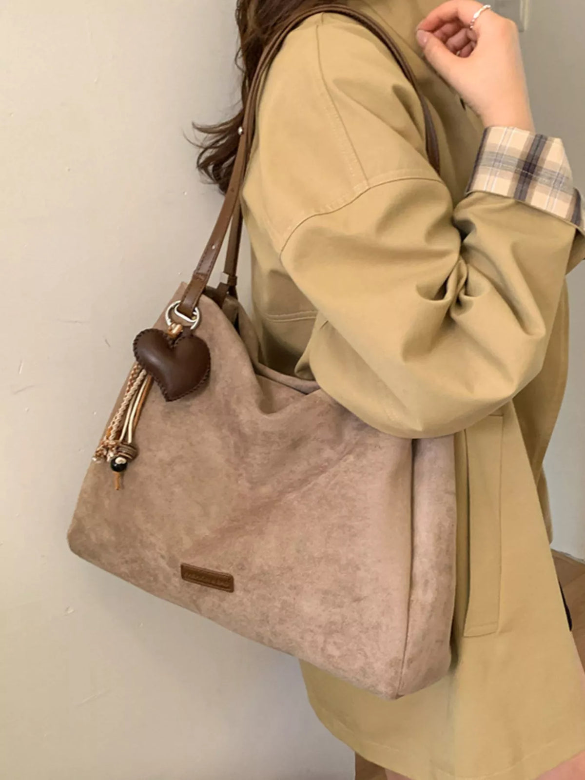 Khaki suede shoulder bag with brown top handles and tassel charm detail
