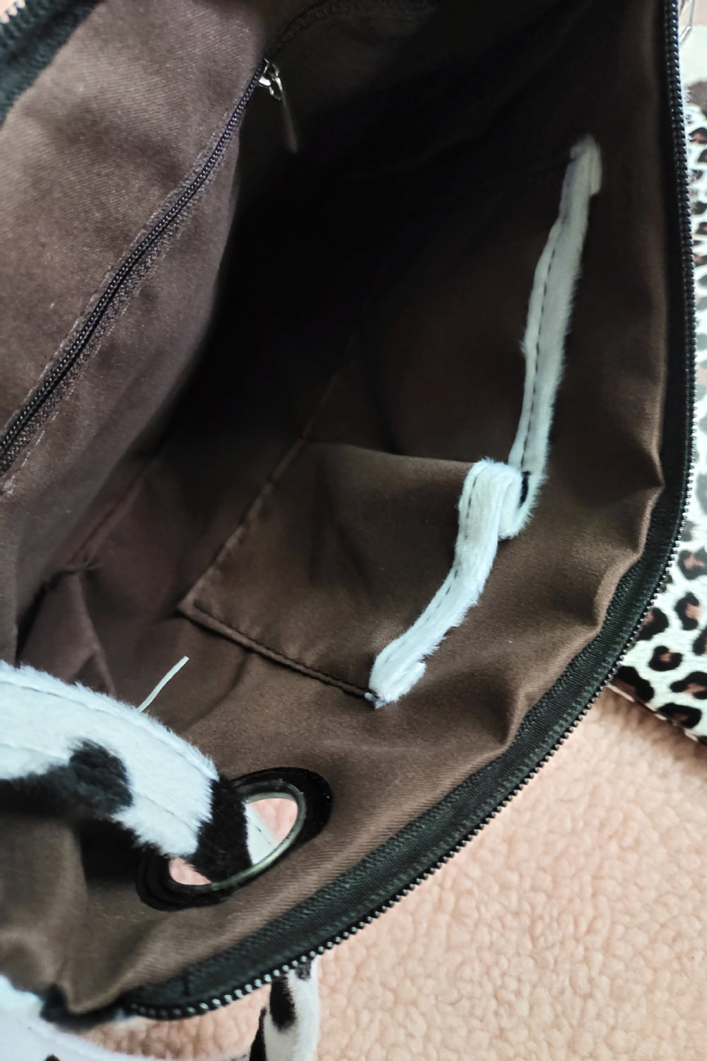 Leopard-print wristlet interior with brown lining, plush fur trim, and strap loop