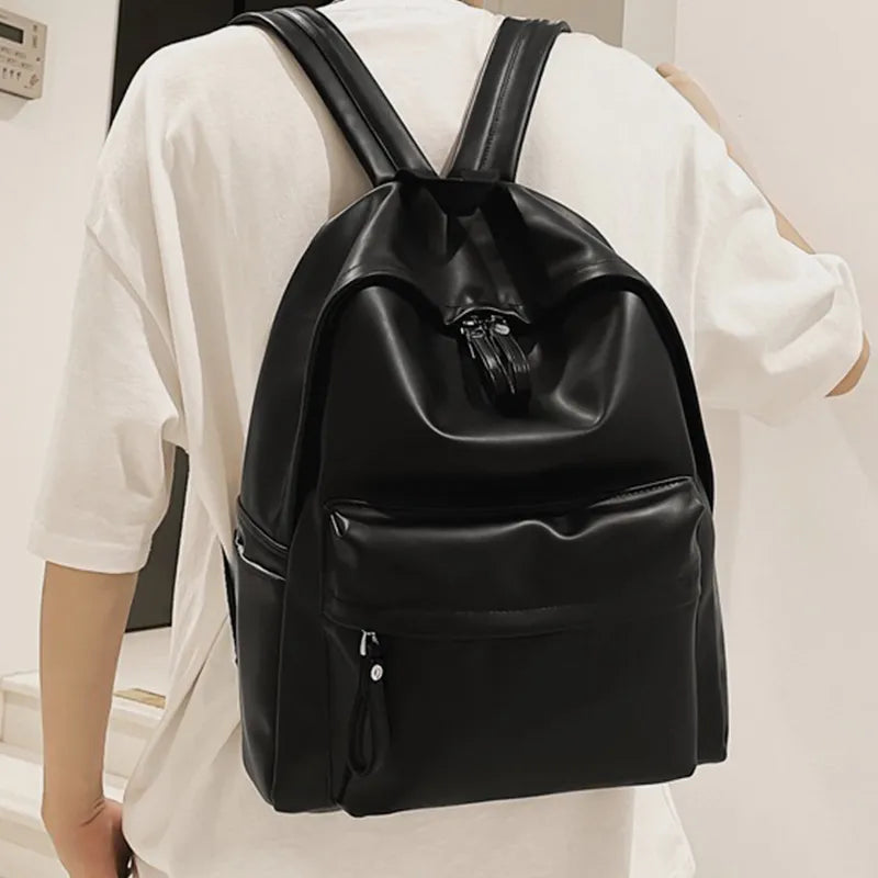 Black vegan leather zip backpack worn on shoulders with front zip pocket