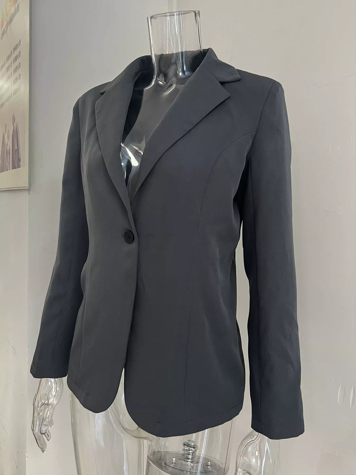 Dark gray slim-fit blazer on mannequin, single button and notched lapels.