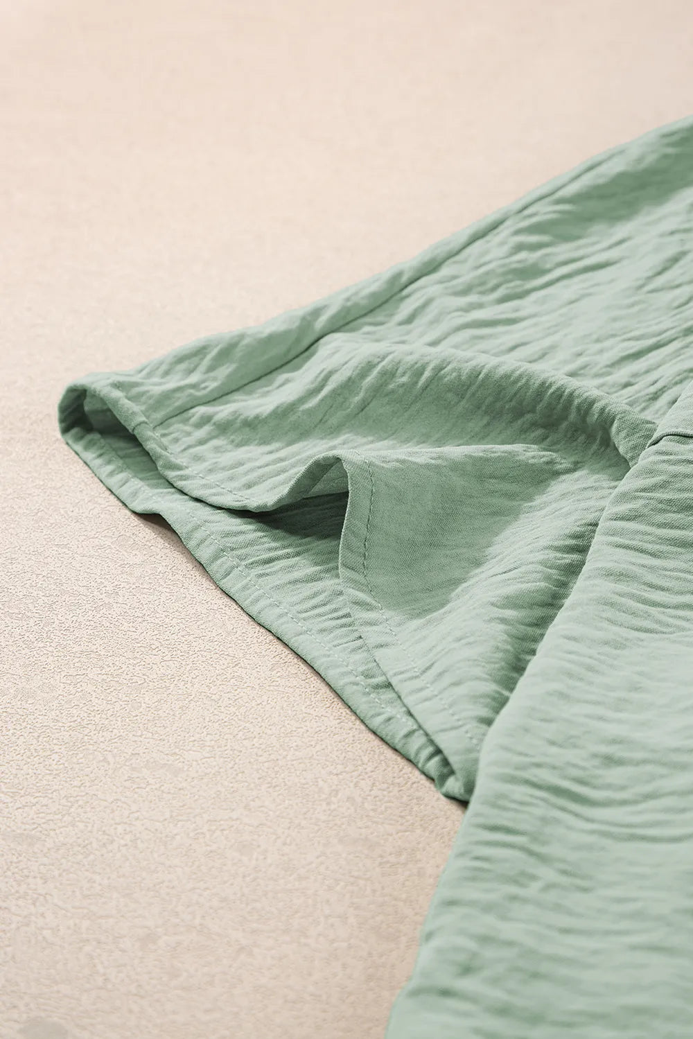 Sage green romper sleeve edge and fabric fold detail