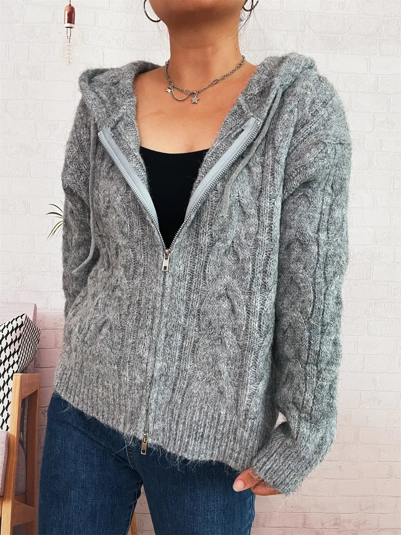 Gray cable knit hooded zip-up cardigan with front zipper and textured knit pattern.