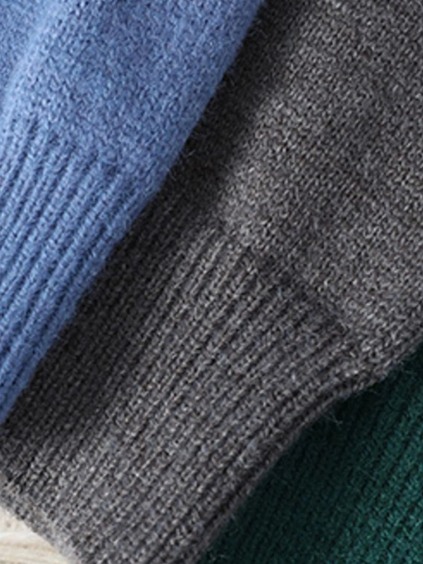Cable knit sweater fabric close-up, heather blue and charcoal knit with ribbed edge